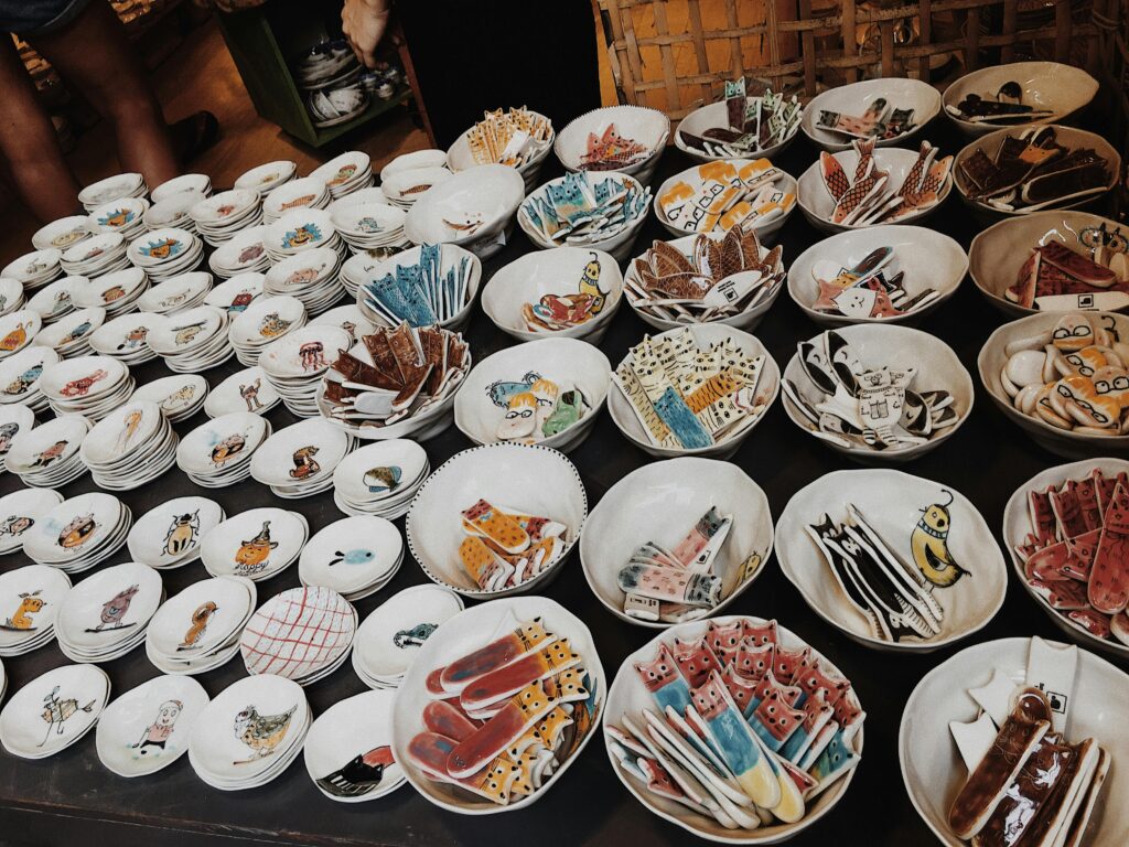 A variety of handmade pottery bowls with unique designs in a Hanoi market display.